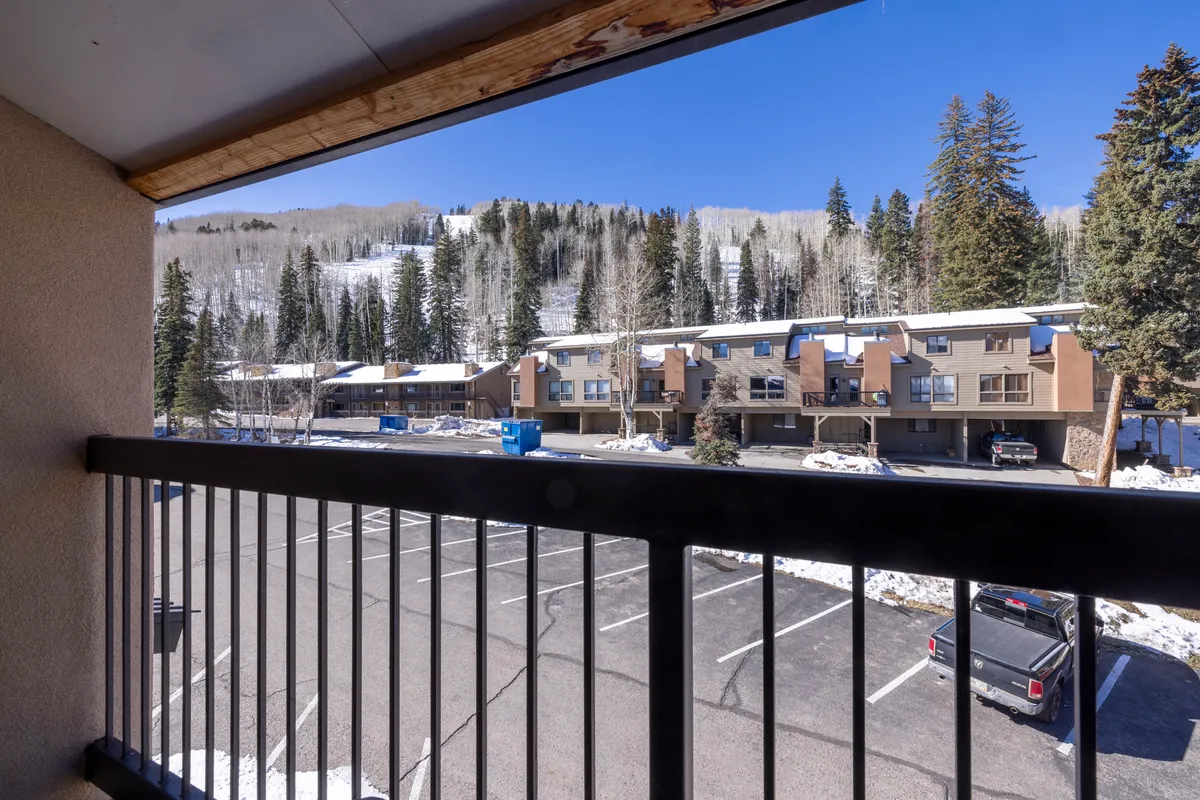A tranquil balcony scene overlooking the surrounding trees and adjacent buildings, perfect for enjoying the crisp mountain air or observing wildlife. The peaceful atmosphere hints at relaxation after a day of adventure.